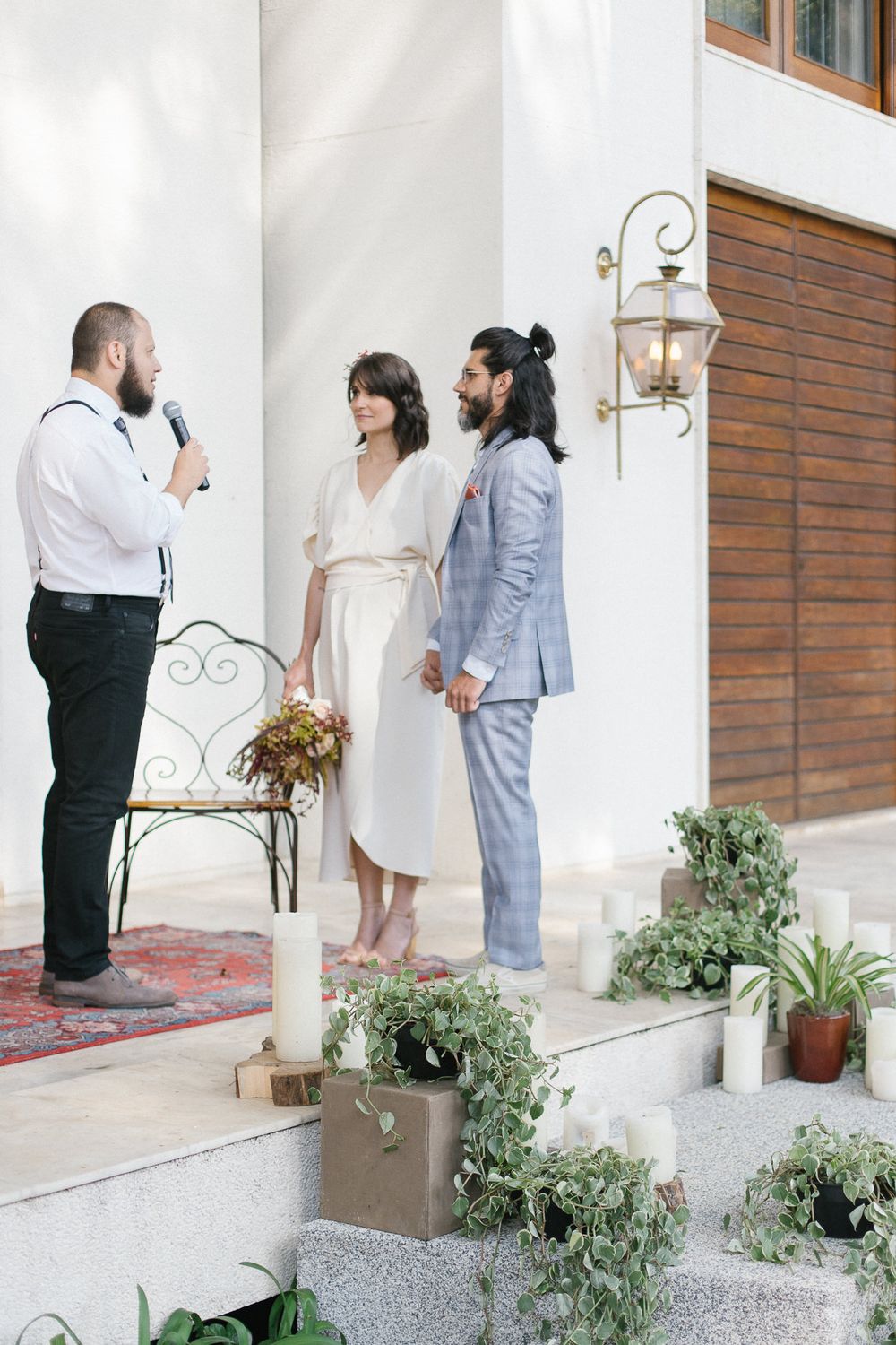 Wedding ceremony on white porch steps with potted plants and vintage metal chair.
