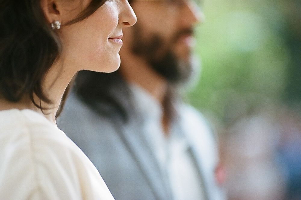 Side profile view of two people in wedding attire against a soft blurred background.