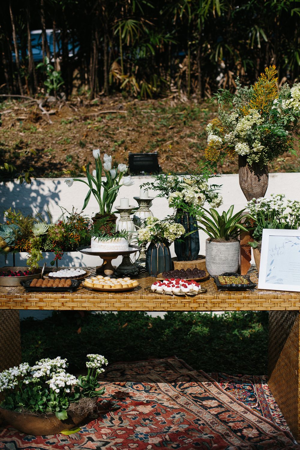 Rustic dessert table with flowers, pastries and decorative elements on vintage wooden surface.