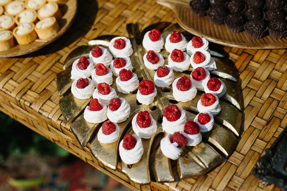 Decorative platter of mini cream puffs topped with fresh raspberries and whipped cream.