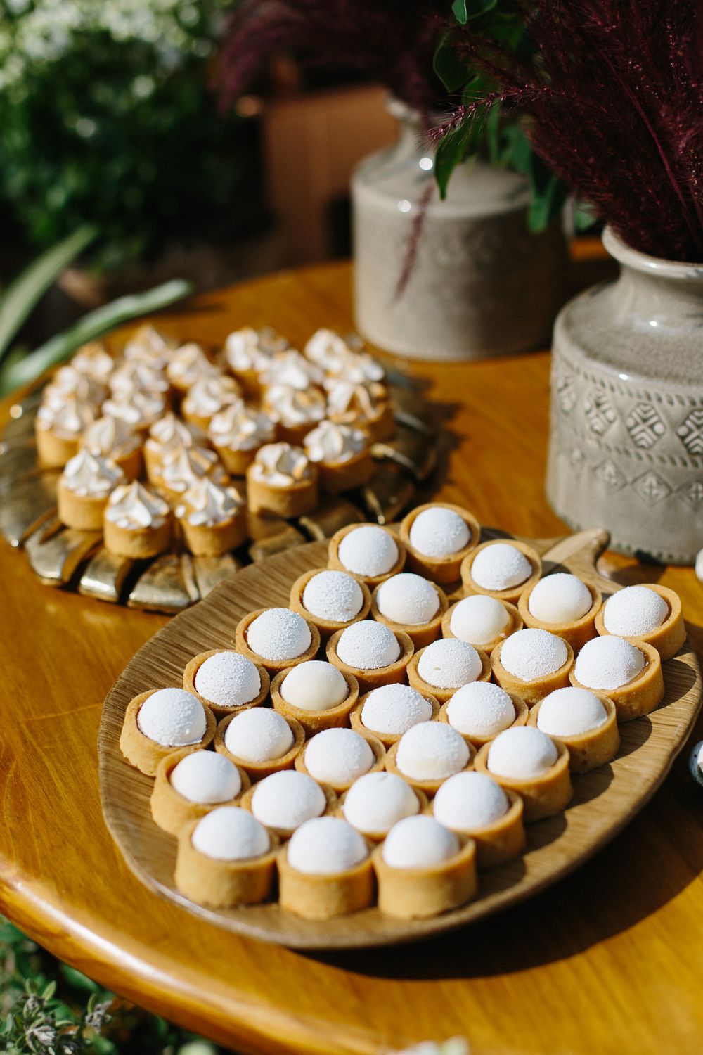 Elegant display of white frosted mini desserts on wooden serving platters.