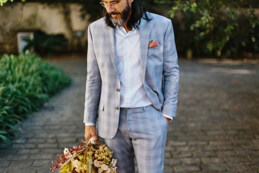 Elegant grey suit with coral pocket square against outdoor garden background.