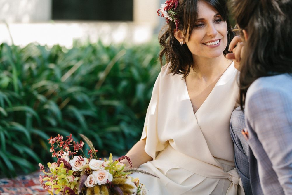 A couple shares a romantic moment outdoors while sitting with floral decorations.