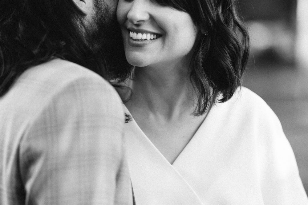 Black and white photo showing a cheerful smile in a white wrap dress.