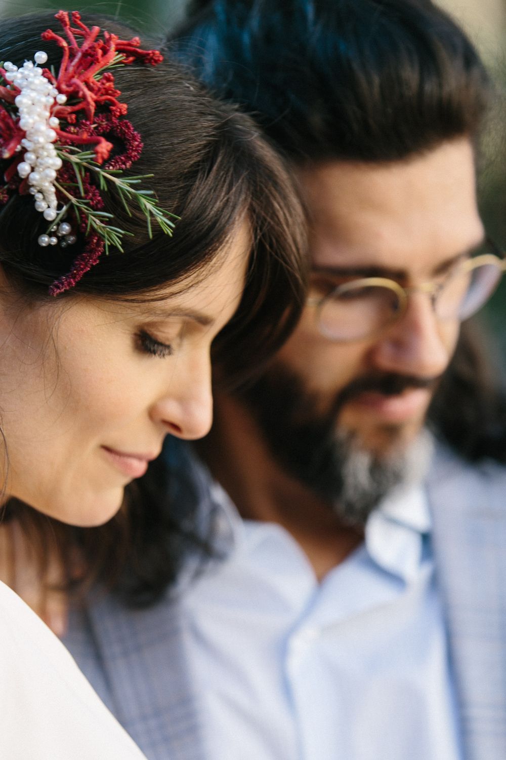 Close-up profile of a couple with floral hair accessories and modern wedding attire.