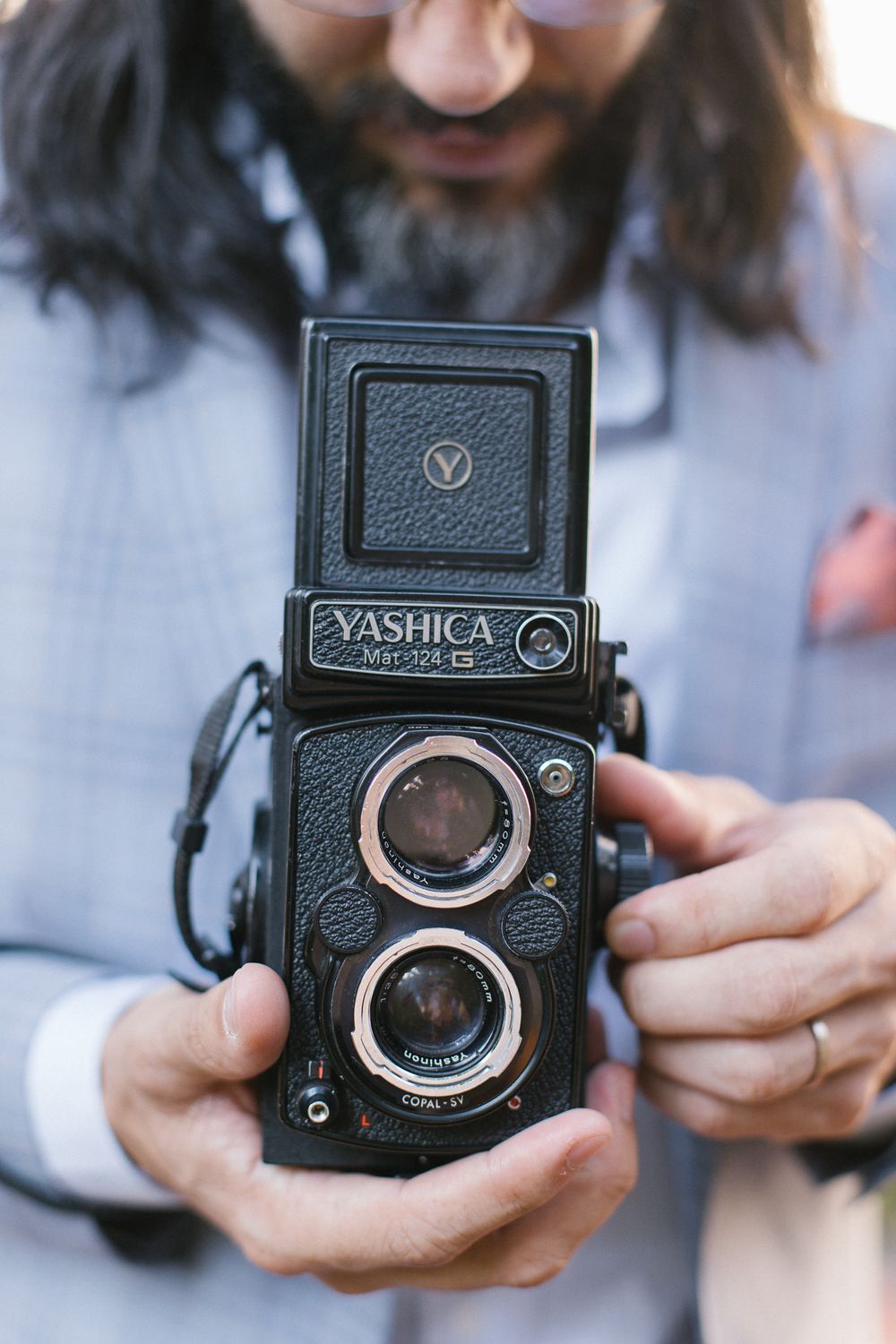 A vintage Yashica twin lens reflex camera being held by someone wearing a light colored sweater.