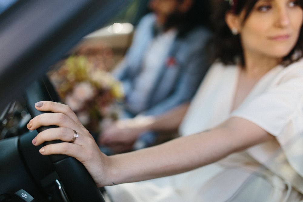 A hand grips a steering wheel while wearing a white garment.
