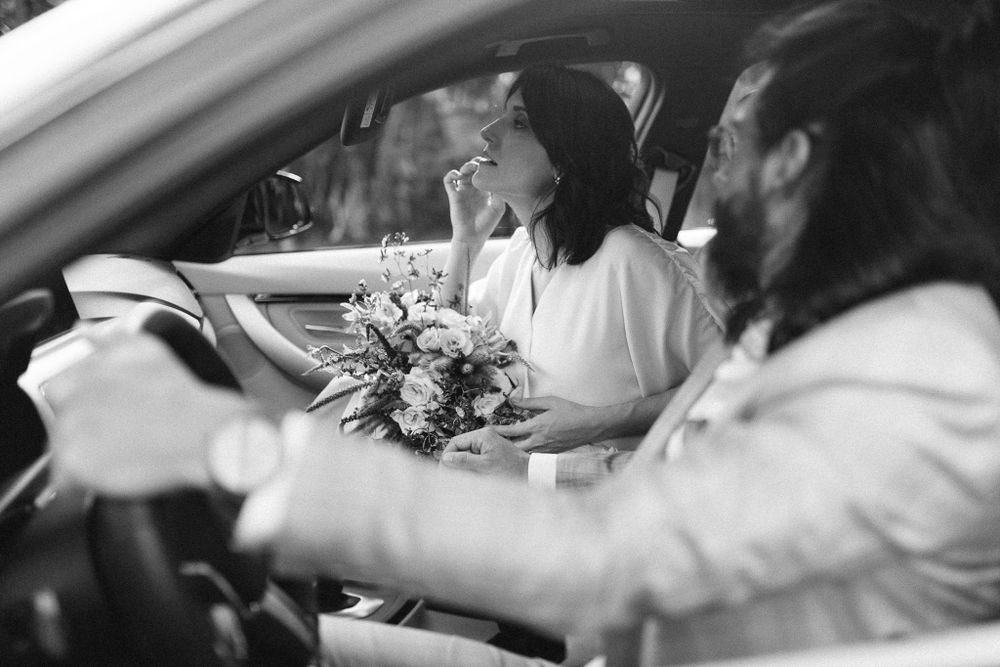 Black and white photo of people in a car with a floral bouquet.