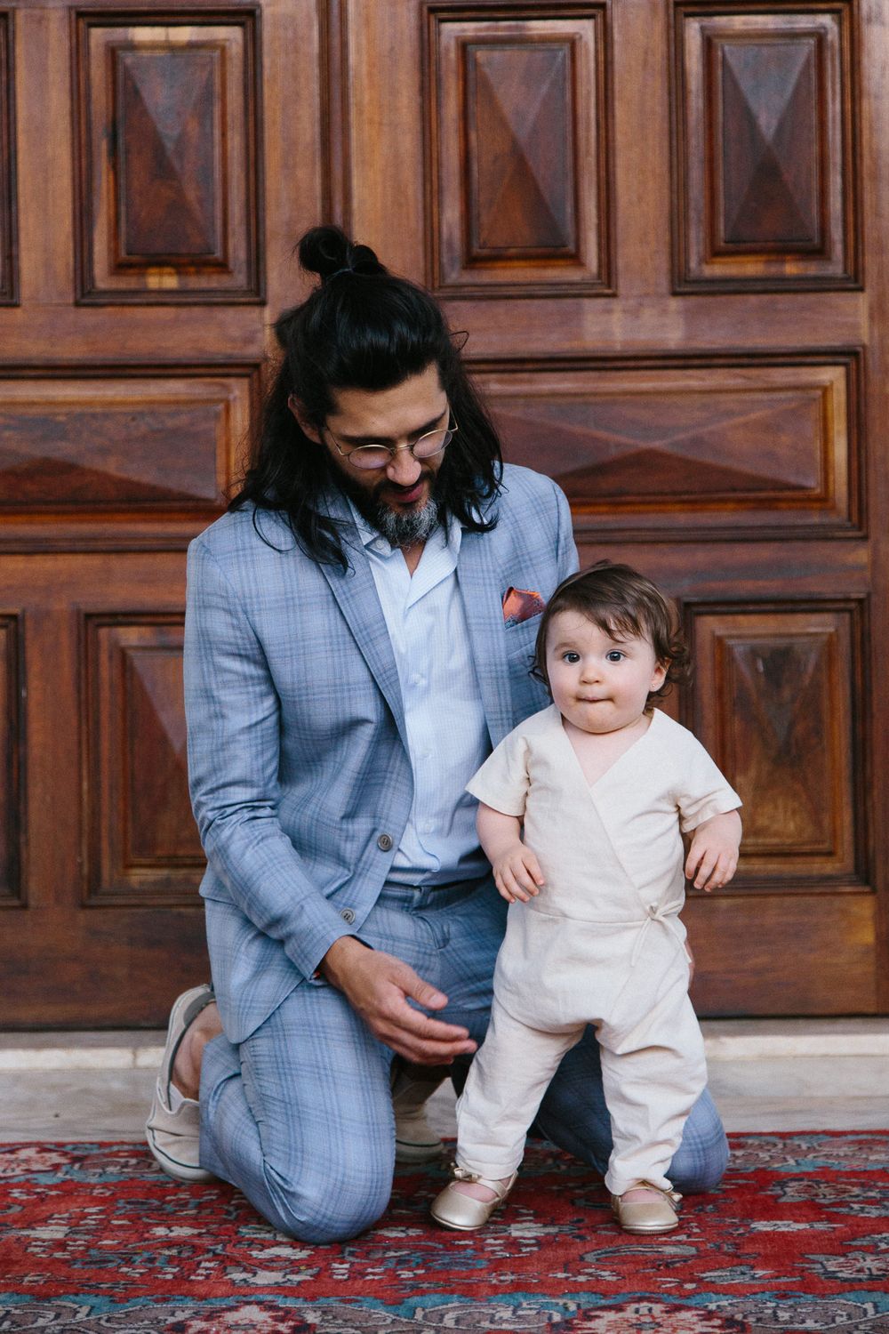 A sweet moment captured between parent and toddler against ornate wooden doors.