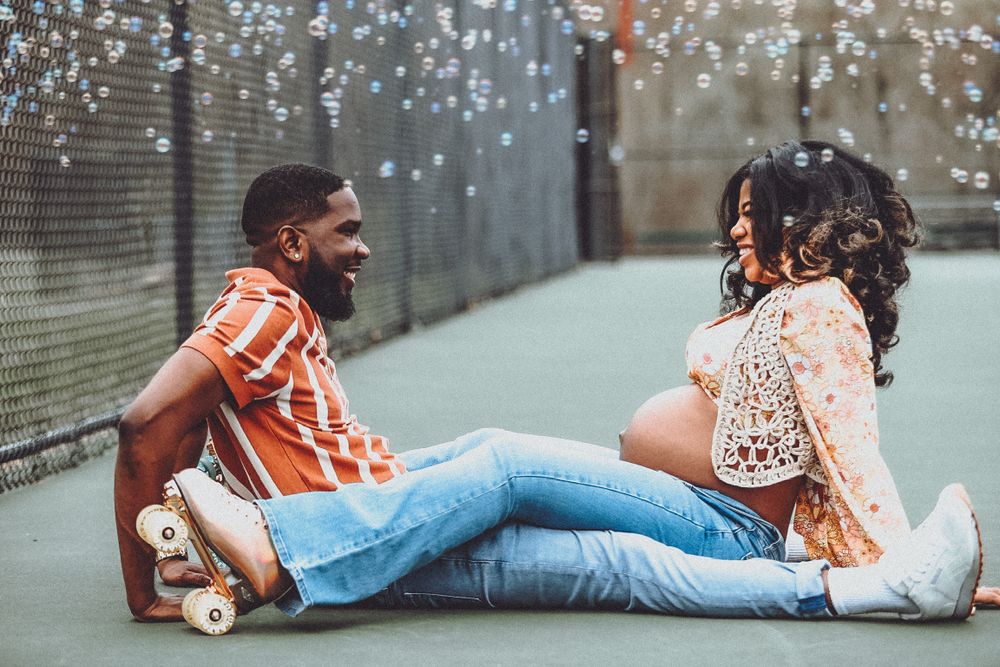 Expecting couple sits together on roller skates for playful maternity photo.