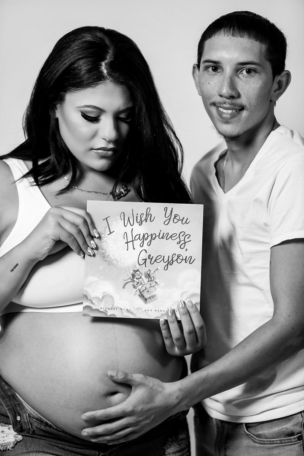 Black and white maternity photo sequence showing couple holding signs with baby wishes.