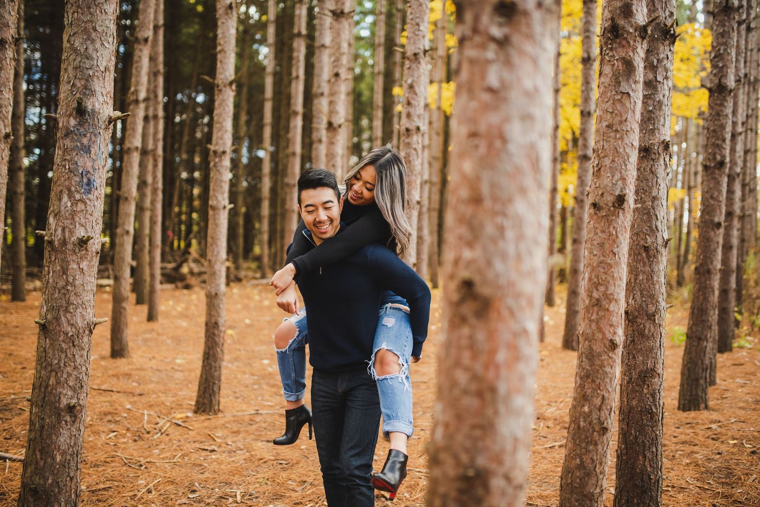 Playful piggyback ride captured in a forest of tall pine trees.