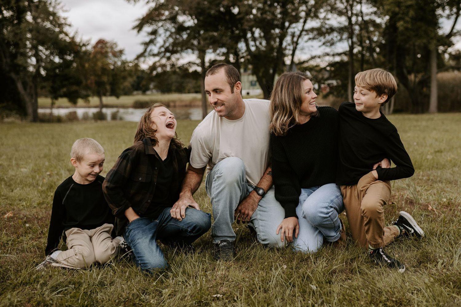 Family relaxes together on grass during golden hour outdoor photo session.