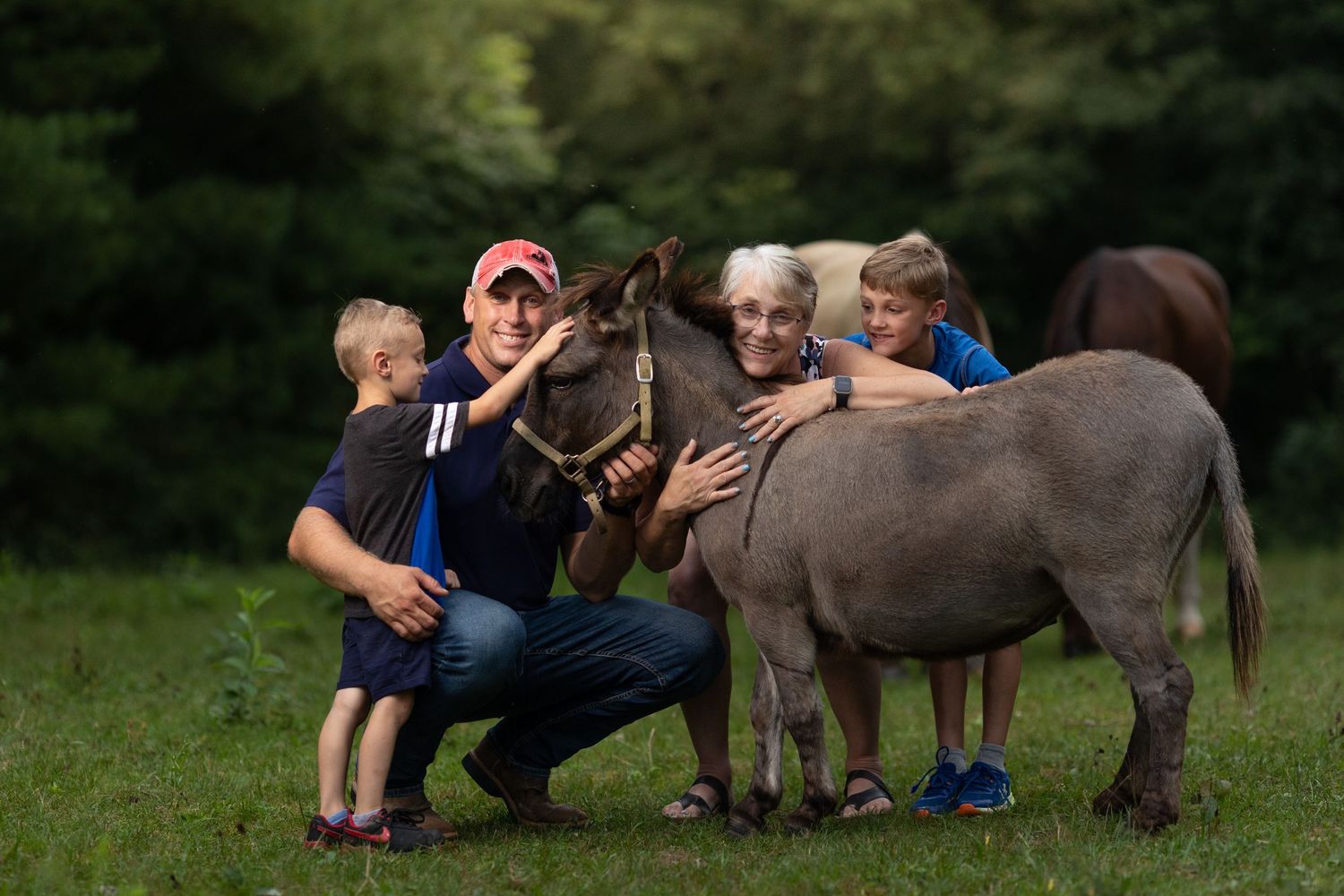 Three generations cuddle a donkey in the Illinois countryside.