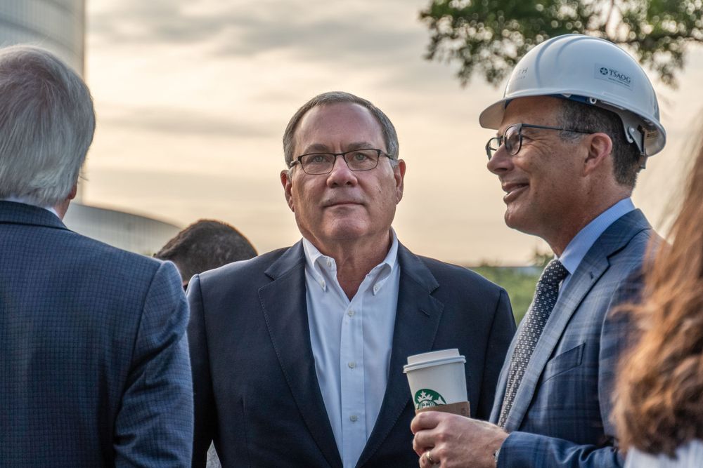 Business professionals gathered outdoors for a networking event on a cloudy day.