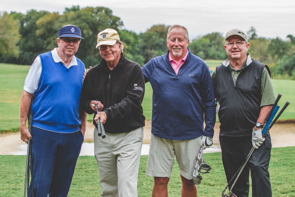 A group of golfers stand together on a lush green course during a casual game.