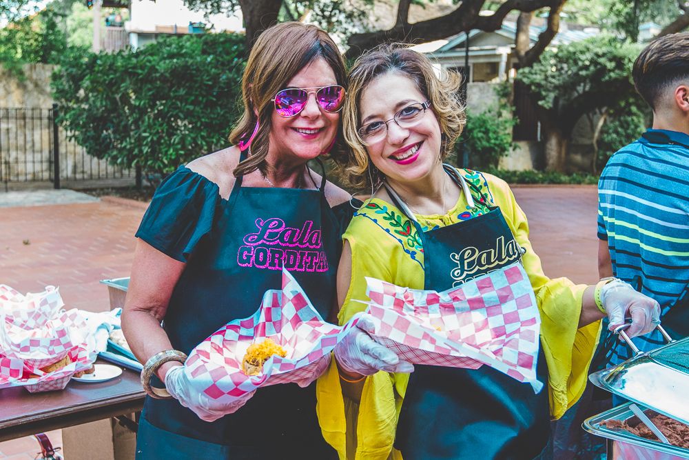Group of people holding colorful gift bags at an outdoor celebration event.
