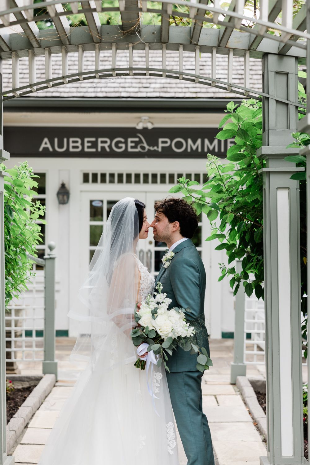 a portrait of bride and groom looking at each other in front of Auberge du Pommier | wedding photographer