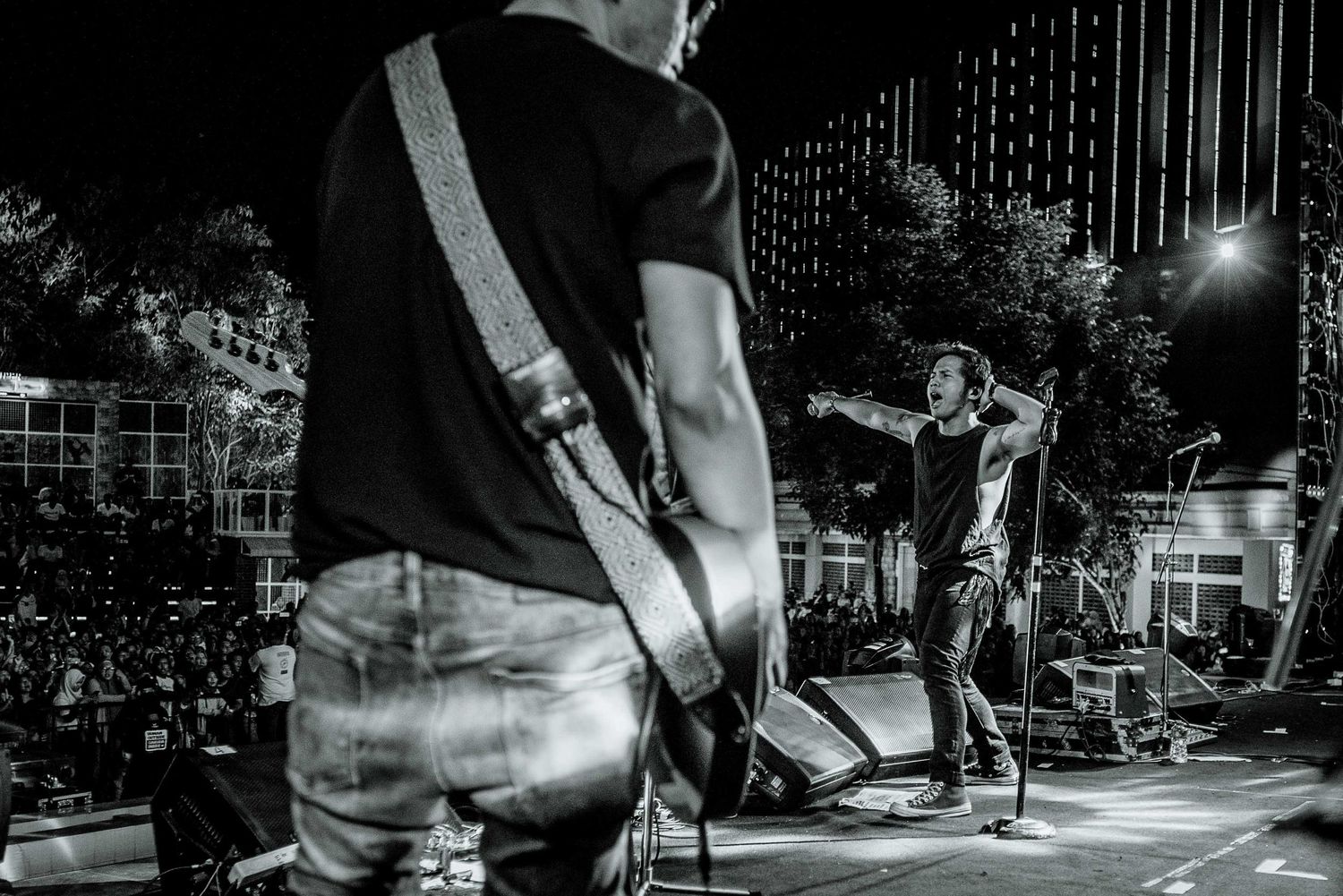 Black and white photo of musicians performing on an outdoor stage at night.