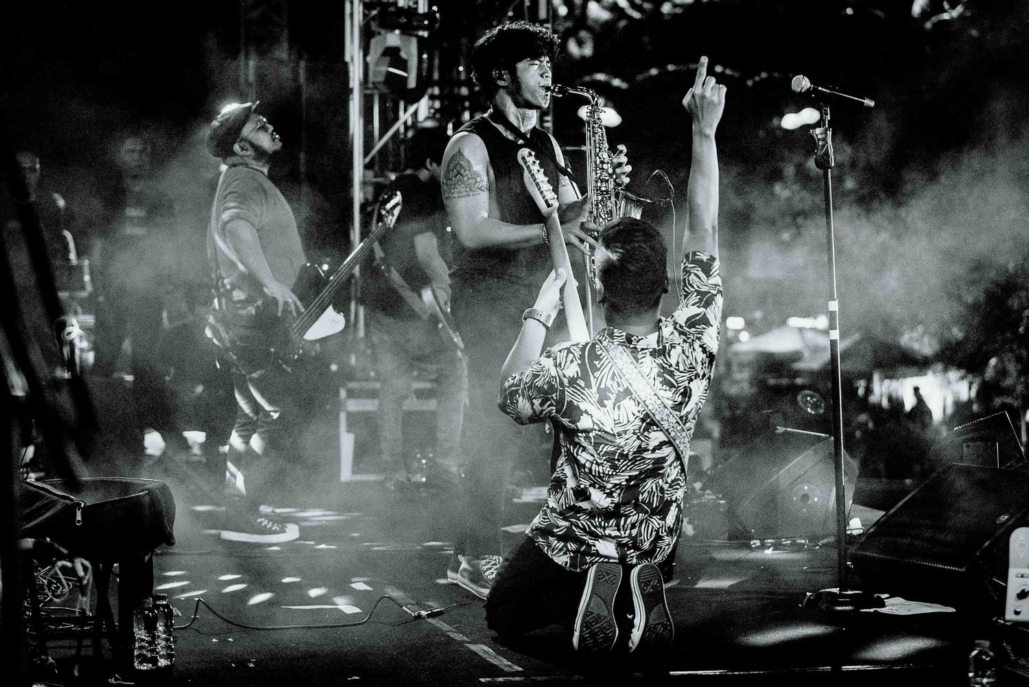 Musical performance captured in dramatic black and white with atmospheric smoke effects on stage.