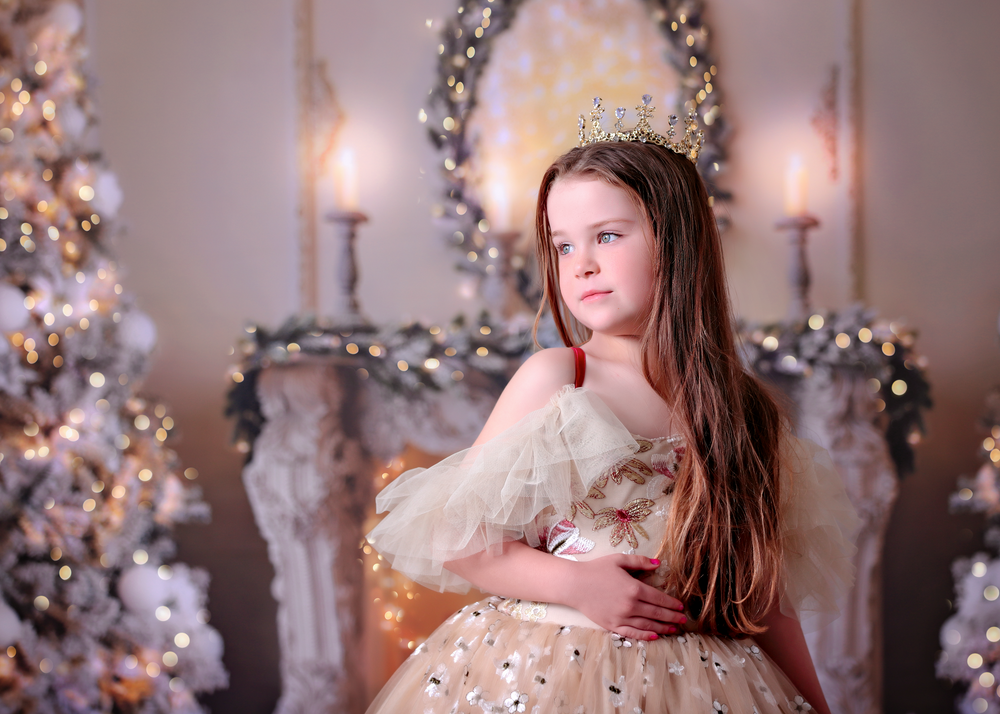 Golden Christmas style Dream Dress session with a girl in a couture gown standing in front of twinkle light lit backdrop
