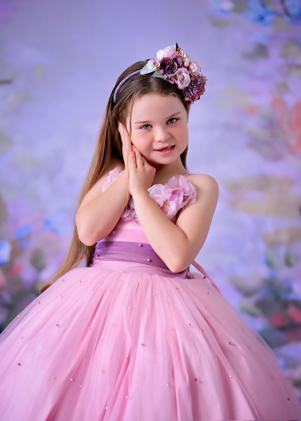 Girl child wearing pink and purple Ombre couture gown in front of floral studio backdrop for a Dream Dress Session.