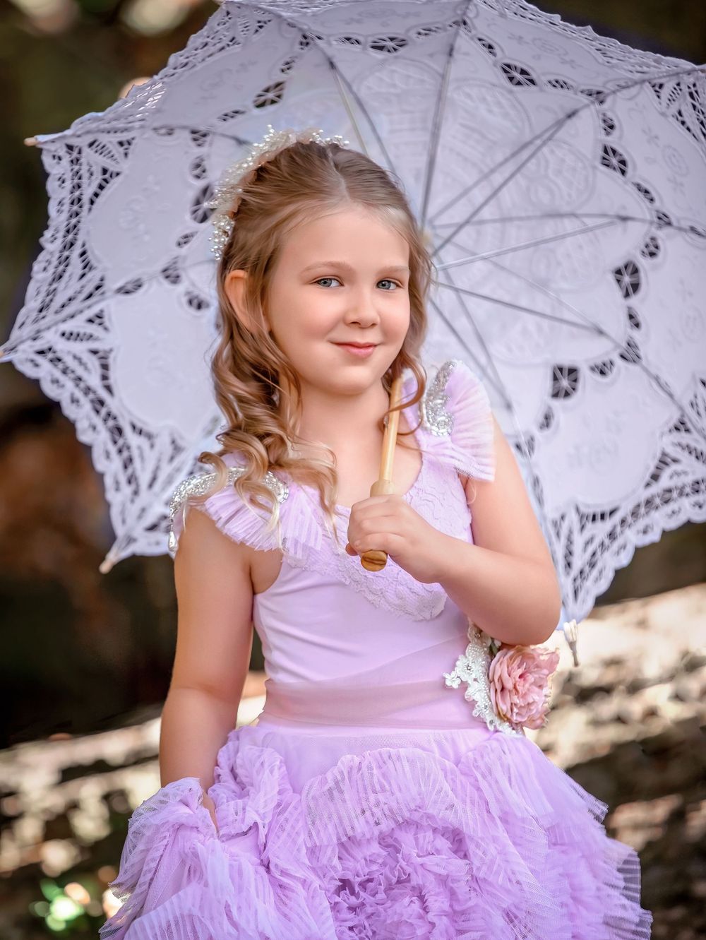 Smiling young girl in purple ruffle gown holding an open white lace parasol over her shoulder for a Dream Dress Session