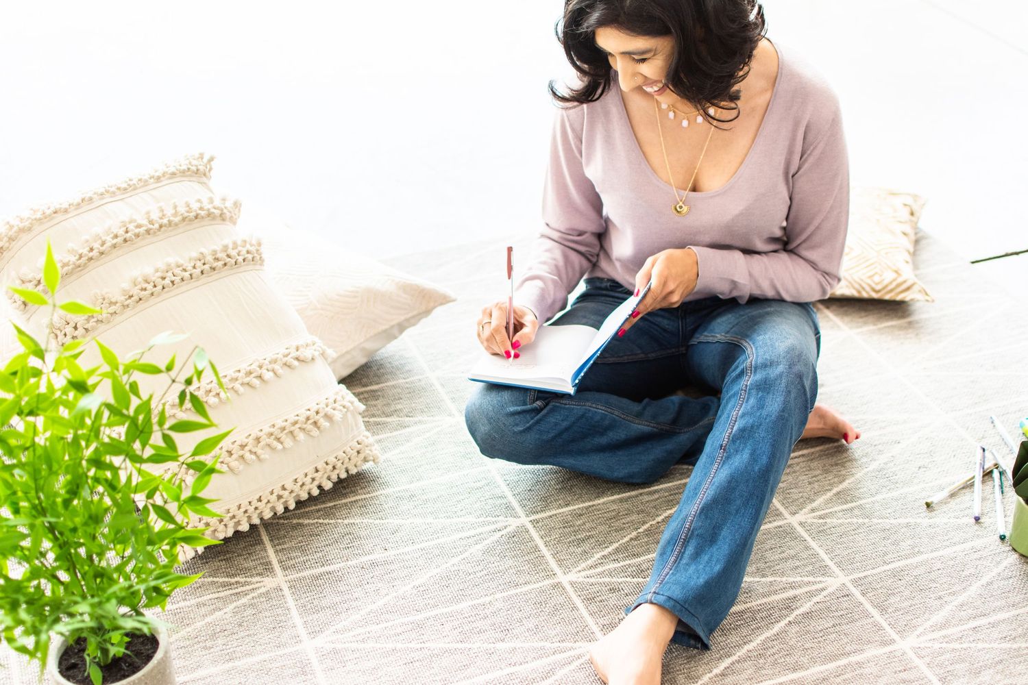 Top view of someone journaling while sitting cross-legged on patterned floor.