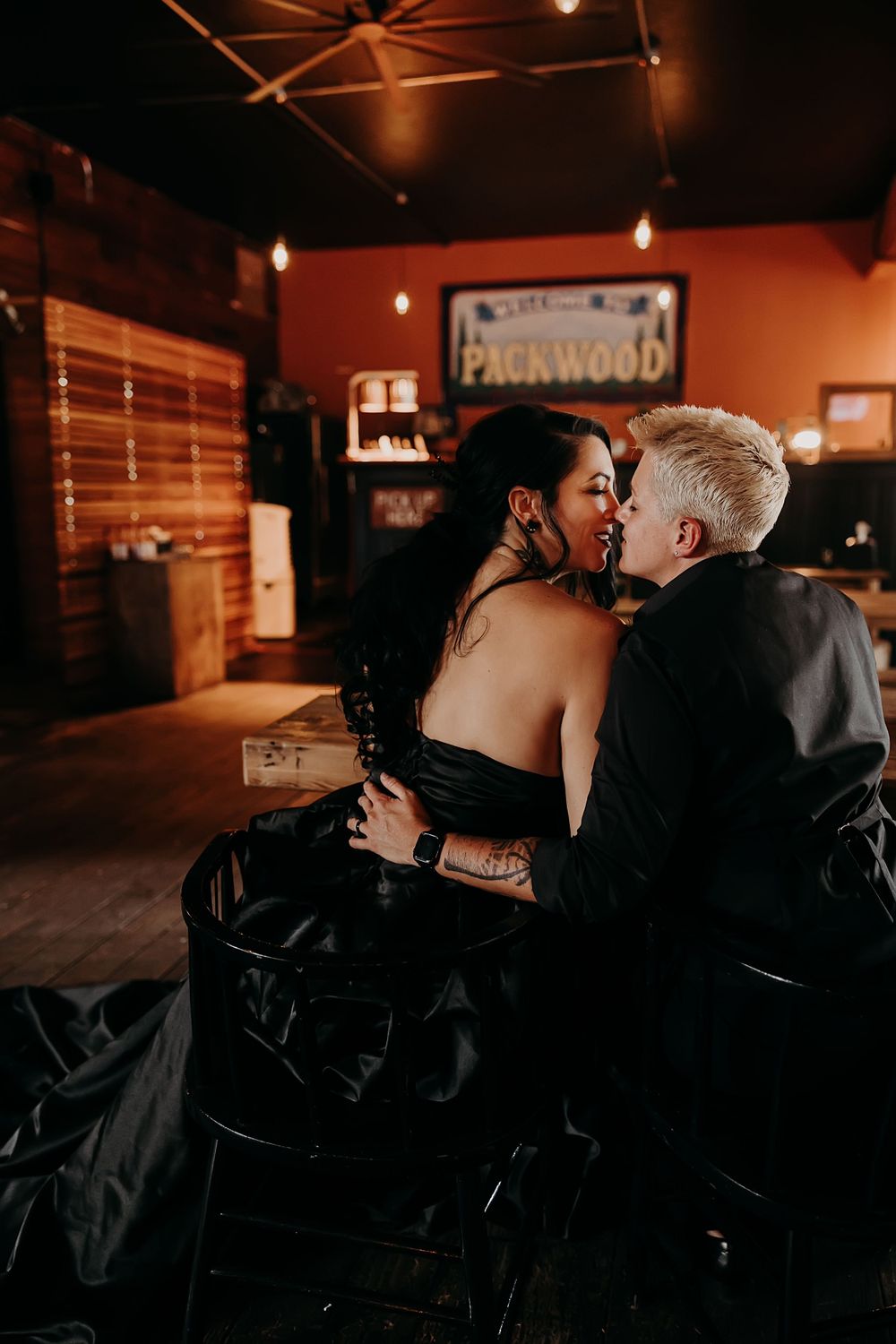 A couple shares a romantic moment at the Packwood bar in warm lighting.