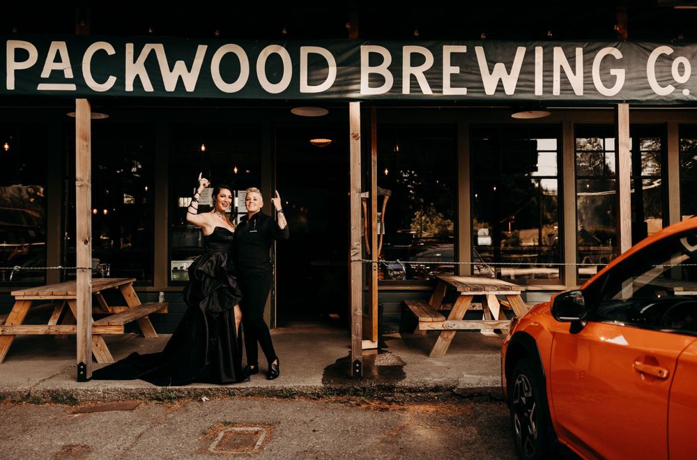A couple poses outside Packwood Brewing Co. at night in formal attire.