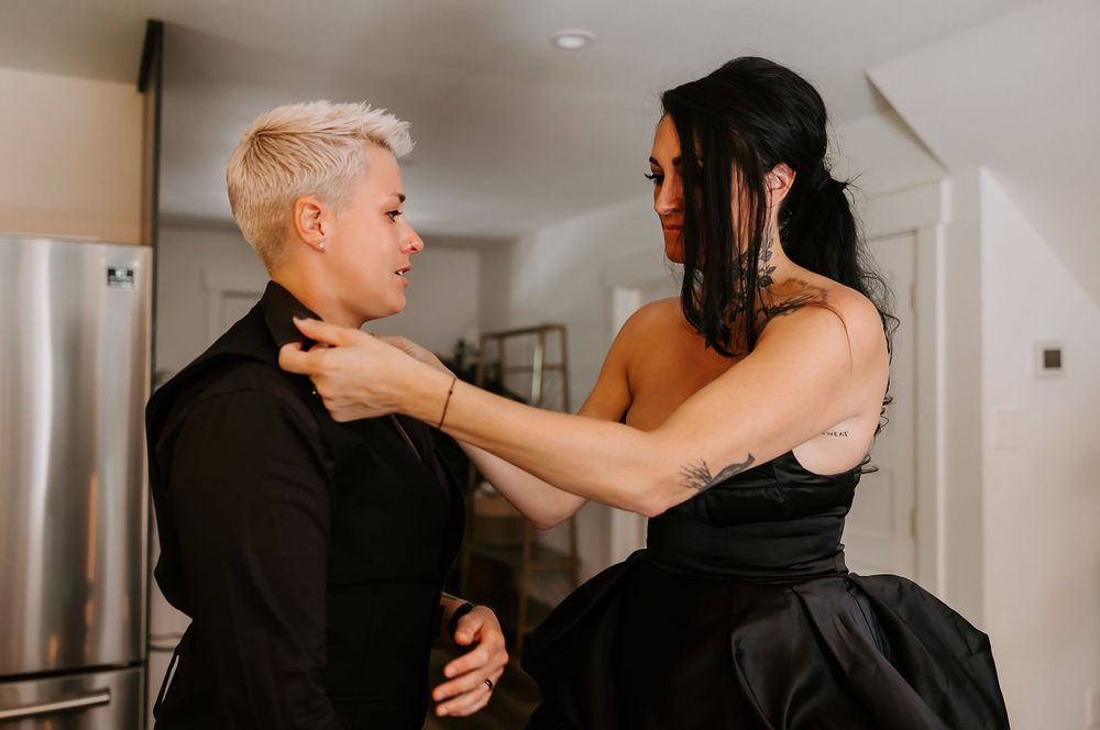 A couple in black clothing sharing an intimate dance in an indoor setting.