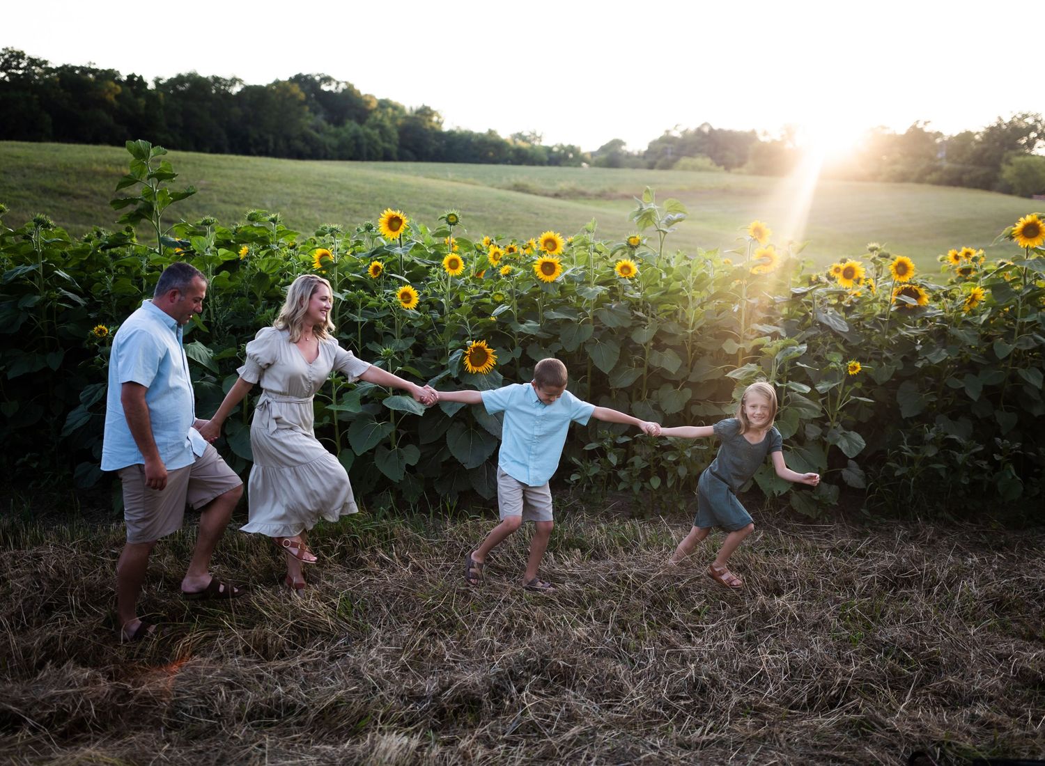 walking holding hands family photo in front of sunflowers