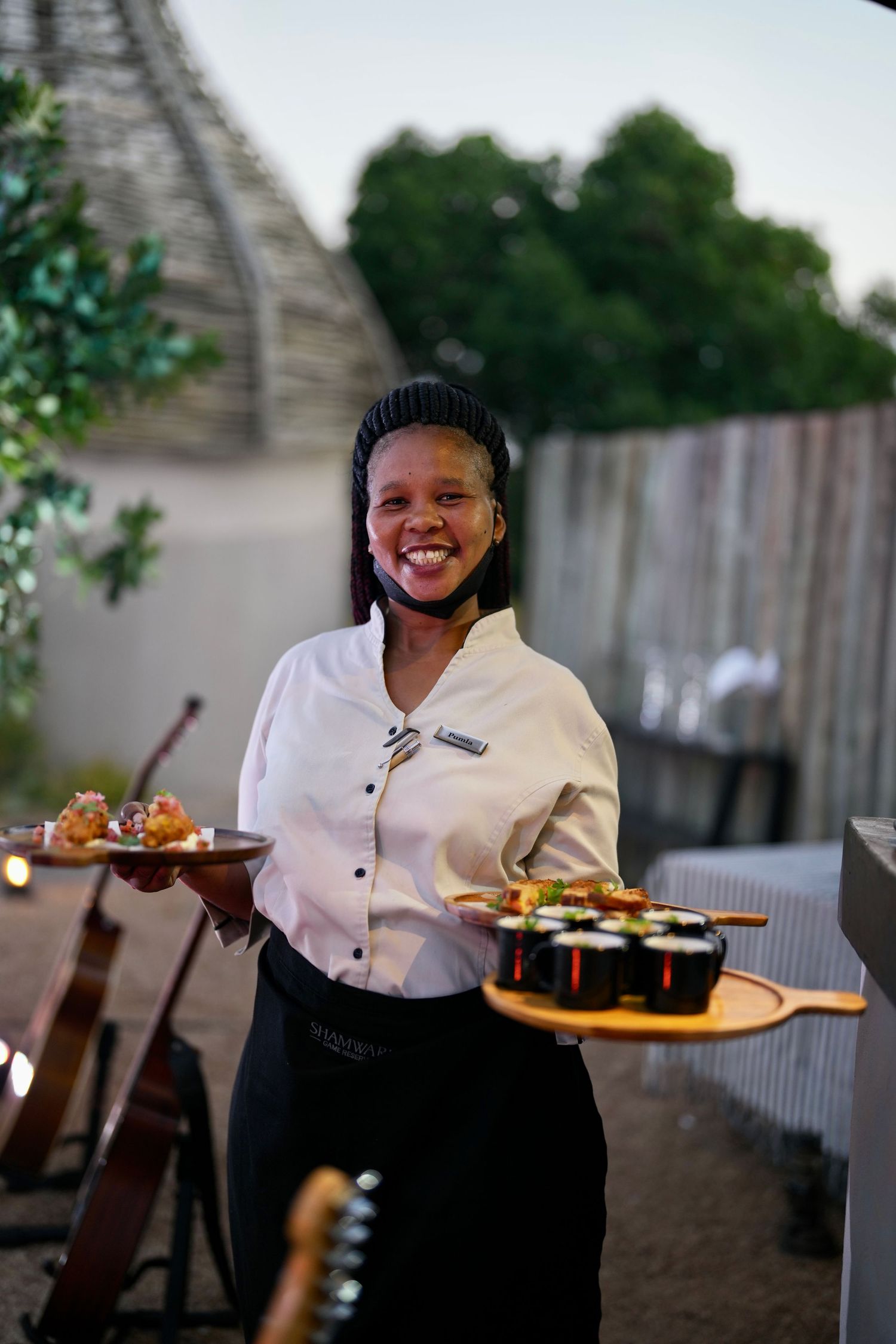 Waitstaff carrying food plates while providing service at outdoor dining venue.