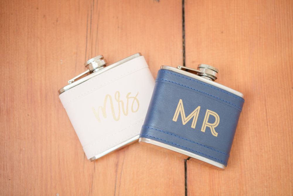 His and hers wedding flask set with Mr and Mrs text in gold on blue and white backgrounds.