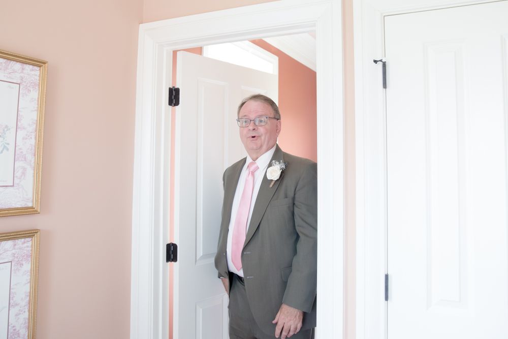 Figure in formal attire standing in doorway with pink walls.