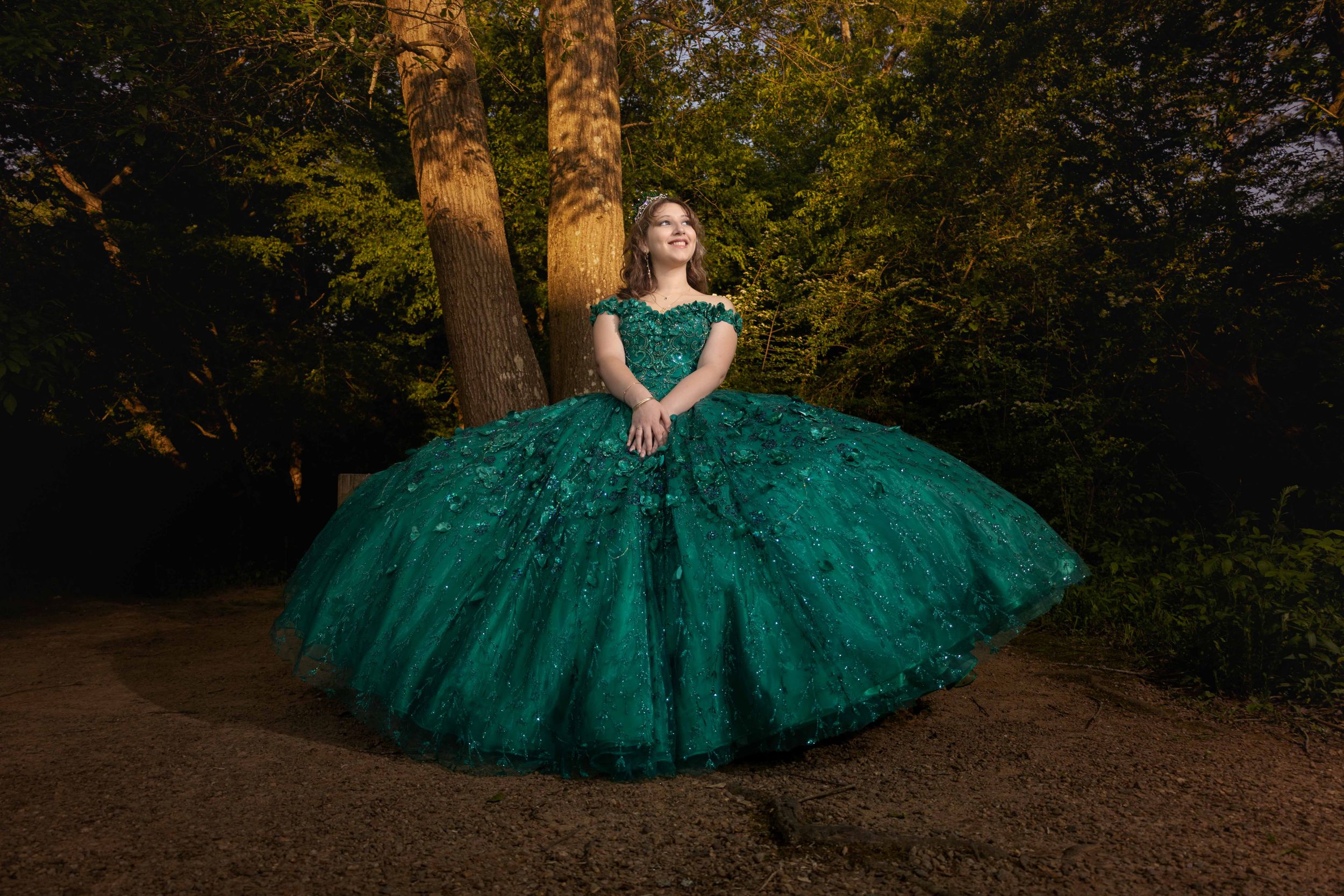 Outdoor portrait session featuring an emerald green tulle gown in a forest setting.