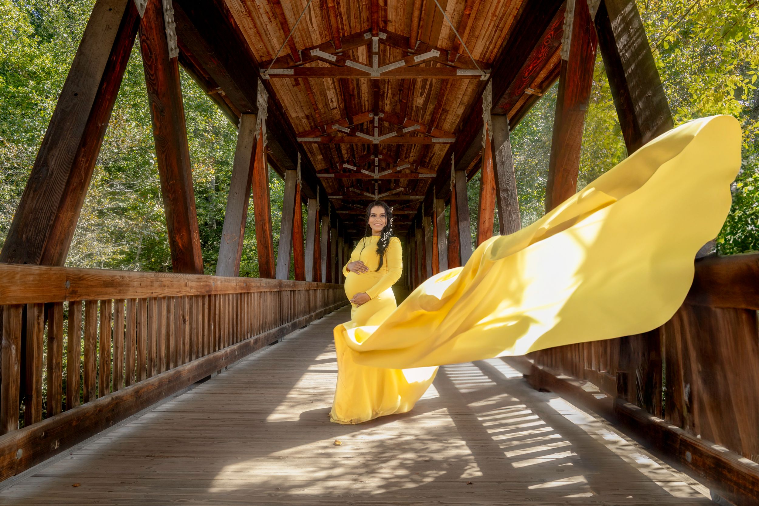 A yellow flowing fabric creates an artistic line through a rustic covered wooden bridge.