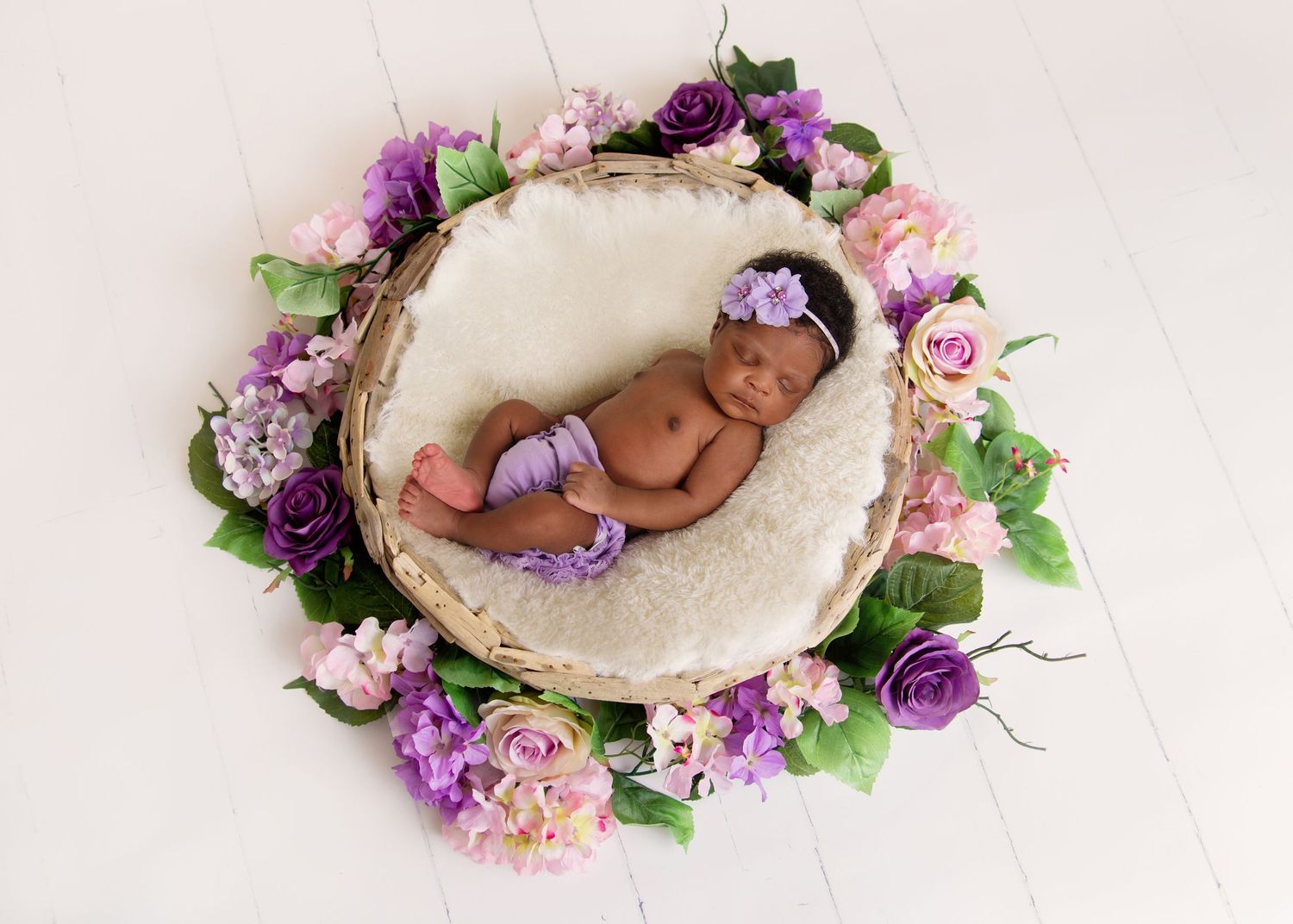 newborn baby girl in flower wreath purple colours