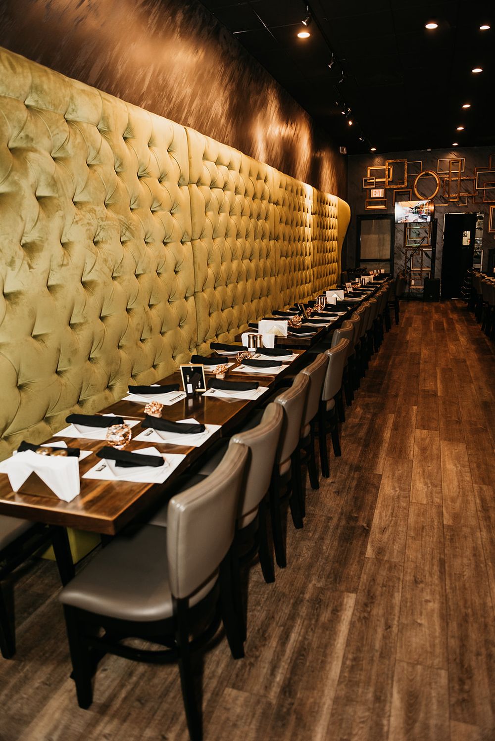 Elegant restaurant interior with tufted wall and place settings along long dining table.