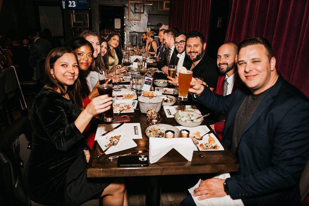 A large group enjoying dinner and drinks together at a long restaurant table.
