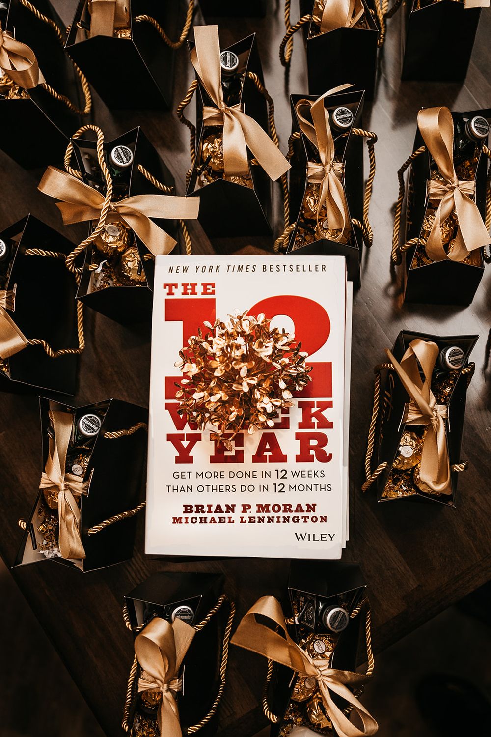 Book '12 Week Year' displayed with decorative gift bags and gold bows.