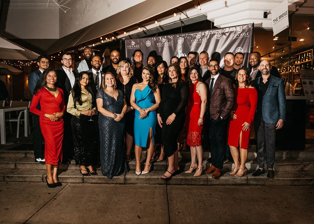 Large group in formal attire poses together at an elegant evening event.