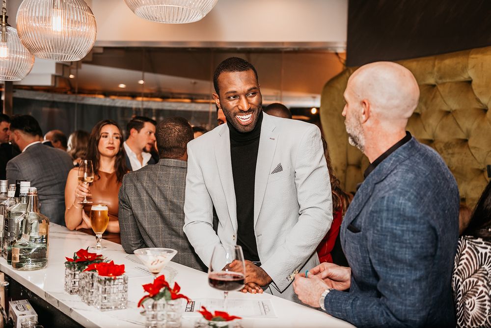 Three people engaged in conversation at an upscale bar with festive red decorations.
