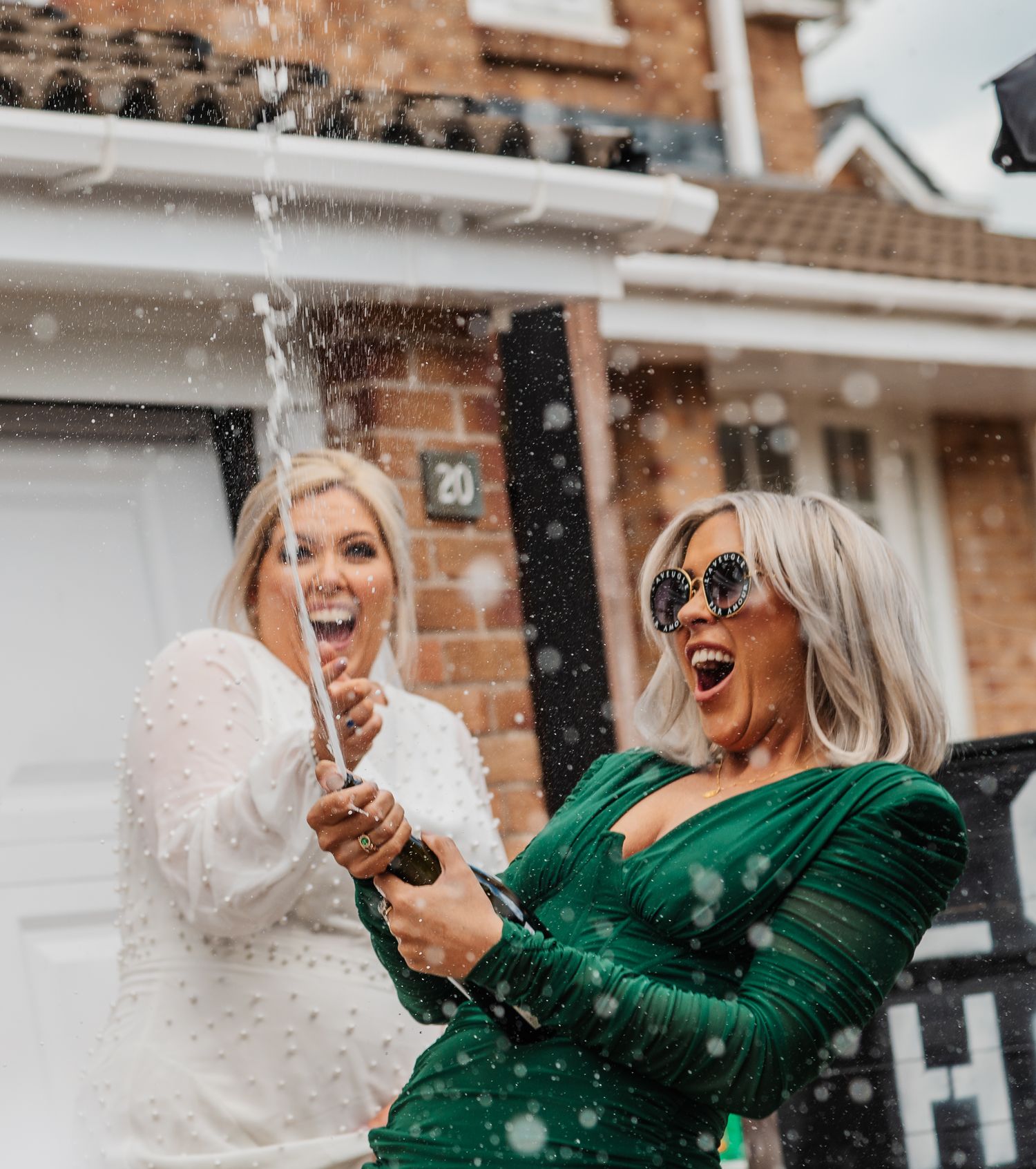 Two guests pop champagne outside with expressions of joy and excitement.
