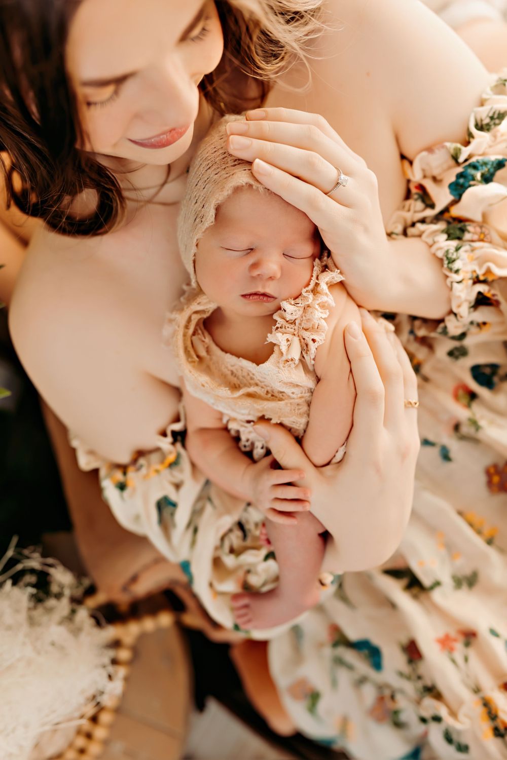 A tender moment between a parent and newborn baby surrounded by floral patterns.