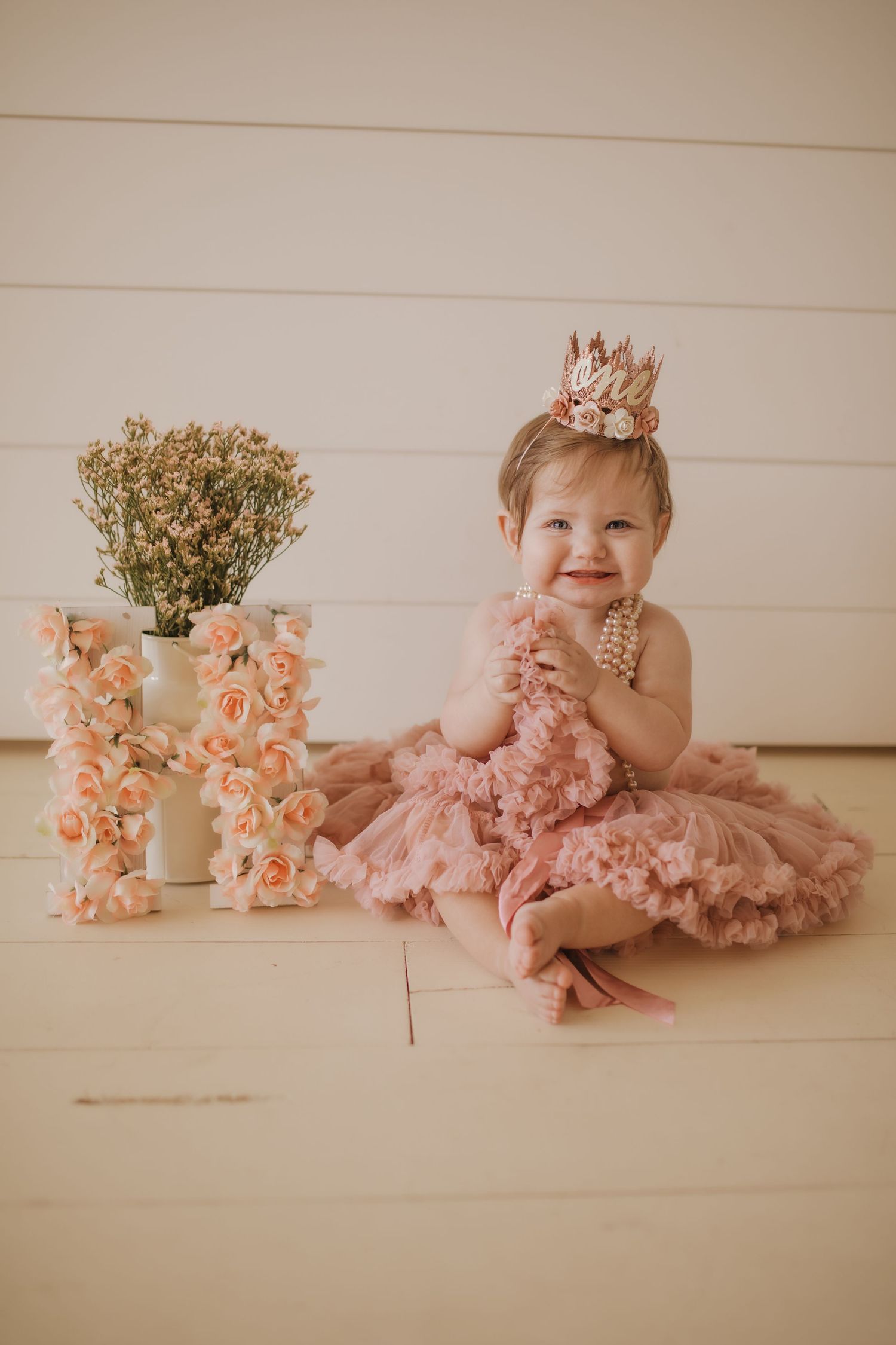 One year old in tutu and a crown with a flower initial