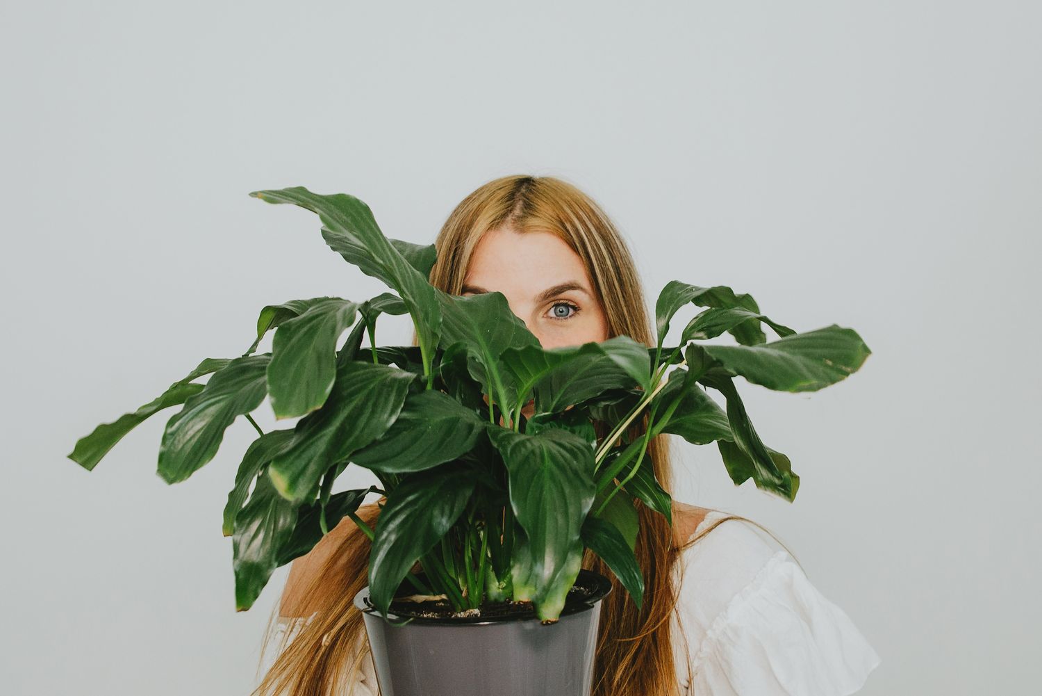 Branding session for an influencer. She holds her plants in front of her face and you can see her eye.