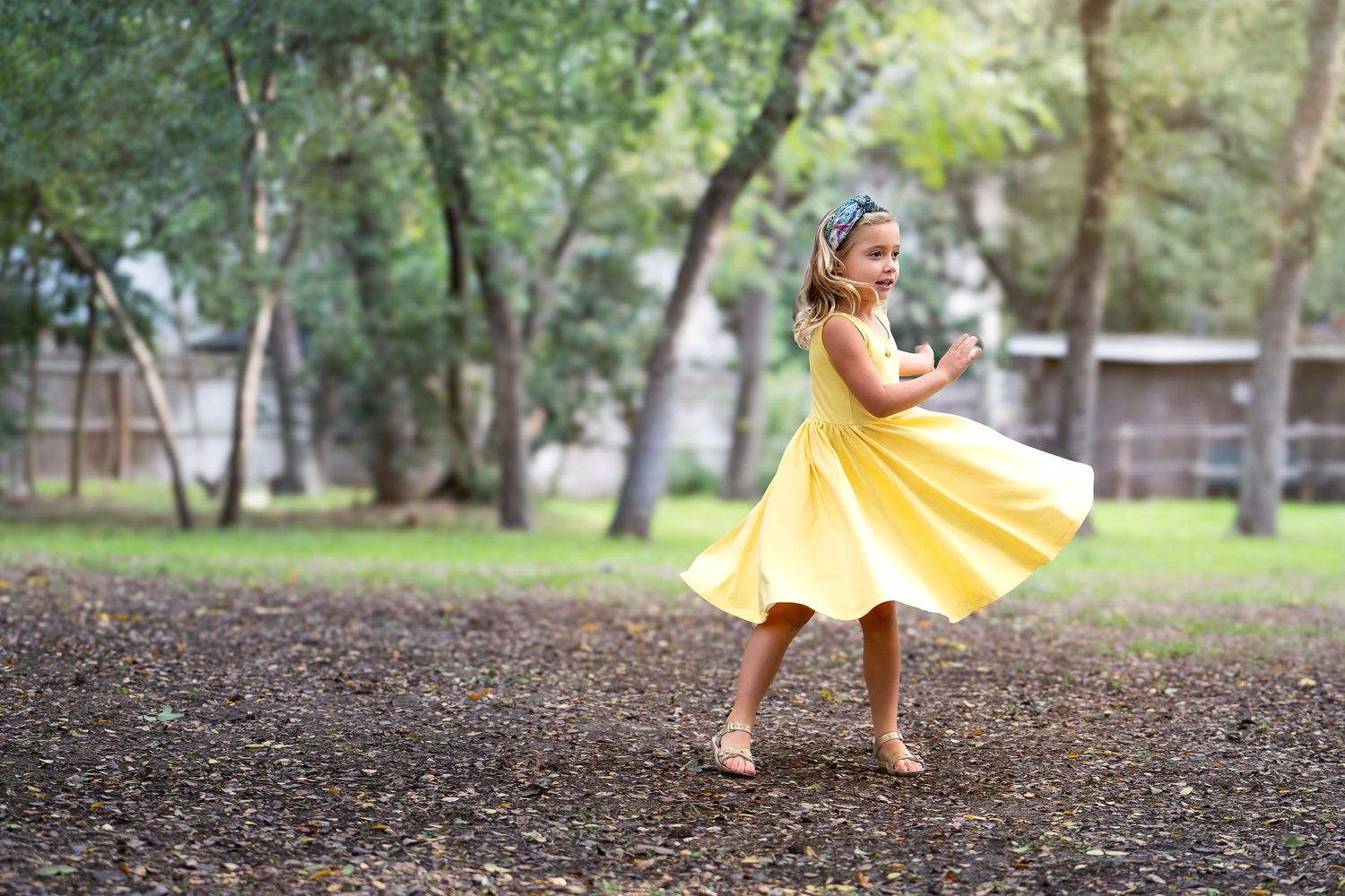 a young girl wearing a yellow sundress twirls in a field at Landa Gardens at Landa Library