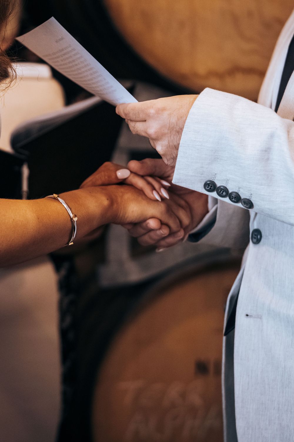 Close-up of hands exchanging rings during wedding ceremony with vows being read.