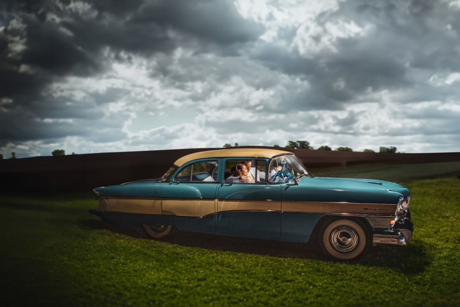 a classic car sits in grass under dark skies, in the style of light teal and navy, candid moments, american barbizon sch